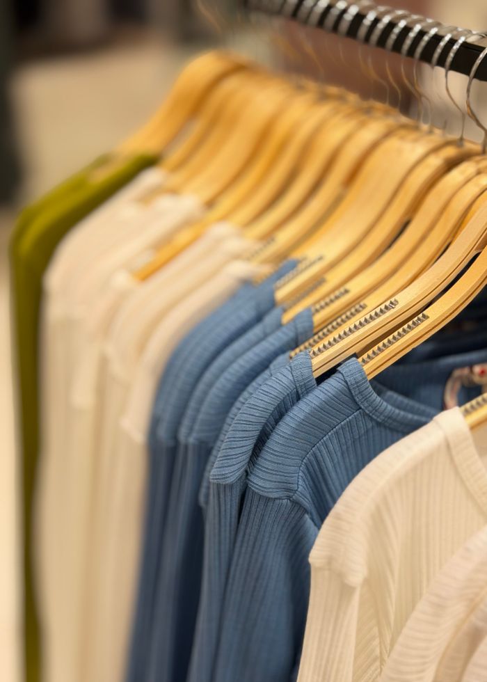 Crafting Captivating Headlines: Your awesome post title goes here A row of neatly arranged colorful clothes on wooden hangers in a retail store setting.